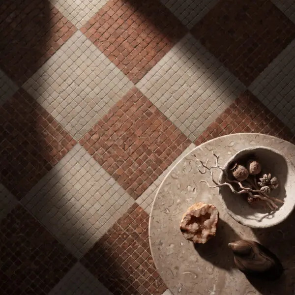 Rust-red and cream Lapicida Roman Rosso Verona mosaic floor tiles laid in a geometric diamond pattern beside a stone table.Close up on floor