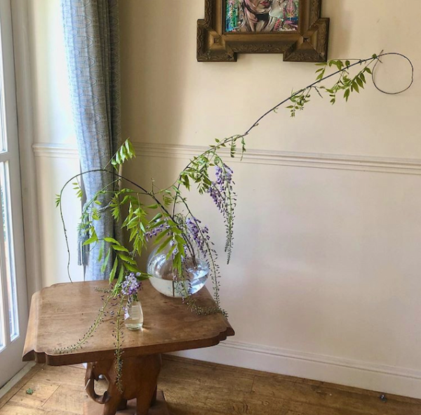Styling foraged finds. Single stemmed flowers in glass vases on a mantlepiece.