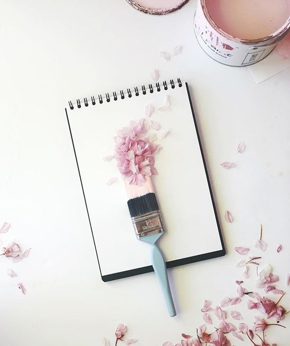 Styling foraged finds from a walk. Pink blossom petals laying on top of pink paint by a paintbrush