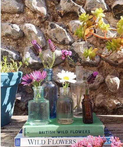 Styling foraged finds from a walk using single stemmed flowers in individual vases