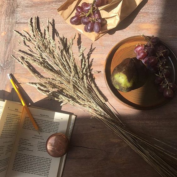 Styling foraged finds from a walk. Flatlay of wheat on a wooden table with fruit.