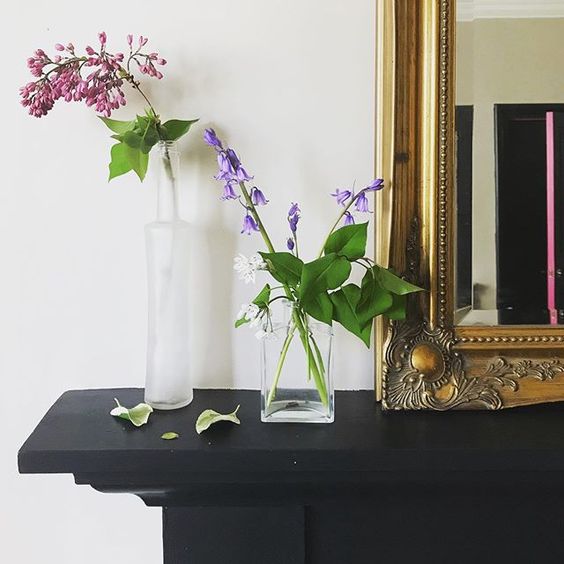 Styling foraged finds. Single stemmed flowers in glass vases on a mantlepiece.