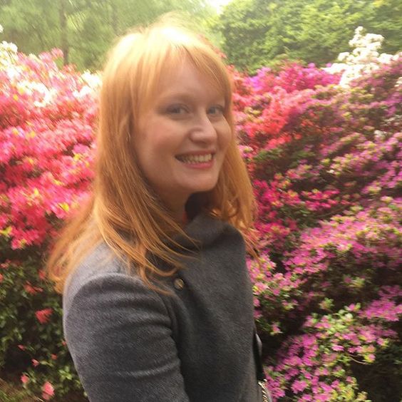 How to use colour in a room.Photograph of a woman with red hair standing in front of colourful azelea