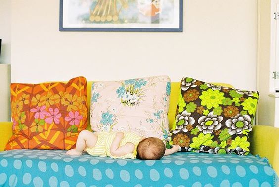 The secret styling tip for adding personality to your home that you need to know! Baby asleep on a sofa with 3 colourful, floral cushions