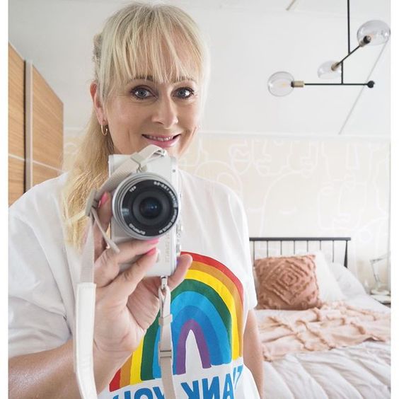 The top UK interior stylists you should be following. Lady wearing a rainbow t-shirt taking a selfie