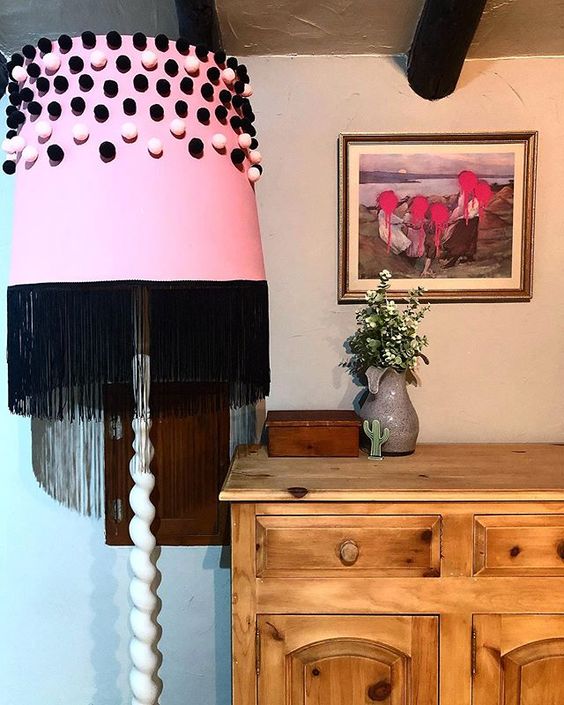 How to use colour in a room. Pink lampshade with black pompoms next to a bedroom dresser