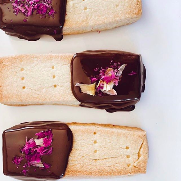 Food styling with shortbread biscuits dipped in chocolate with rose petals