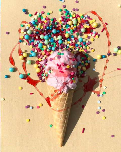 Brightly coloured ice cream with strawberry sauce and sprinkles