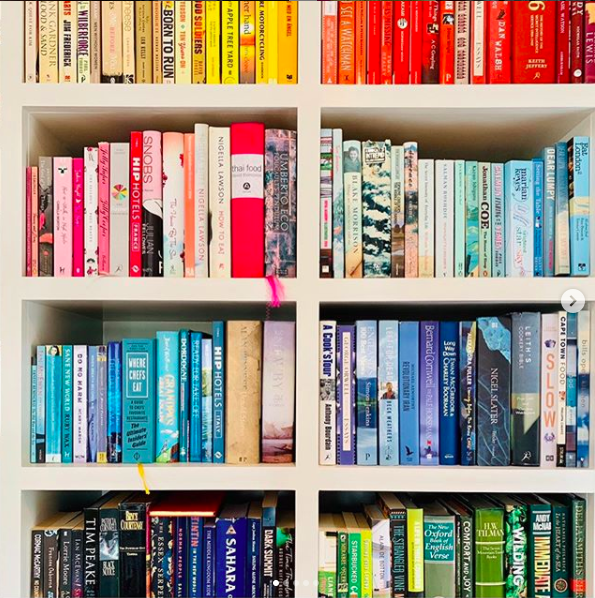 Set of colourful bookshelves with books arranged by colour of their spine.