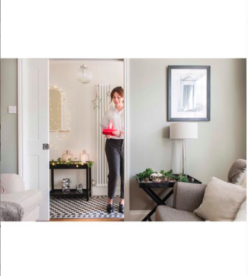 Interior styling shot of a woman holding a Christmas gift in a beautifully styled home