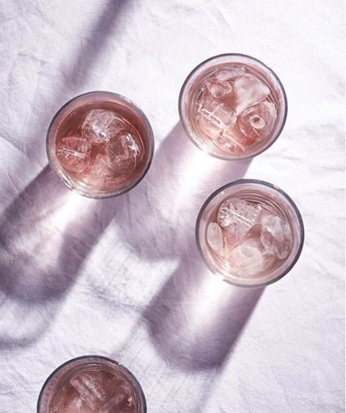 Birds eye view of a still life image of 3 glass tumblers filled with pink juice.