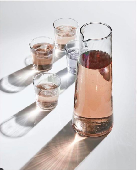 Lifestyle shot of a glass jug and water glasses with pink liquid