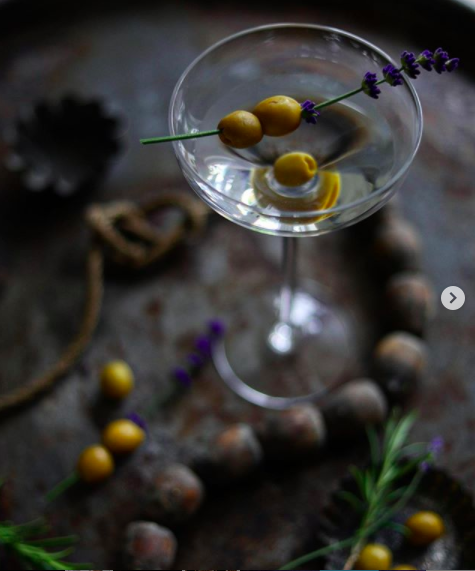 Lifestyle image of a martini glass with green olives