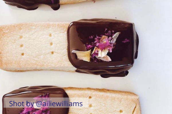 Food styling featuring shortbread biscuits dipped in chocolate with rose petals