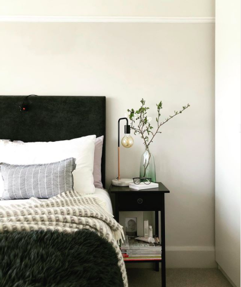 My happy place. Shot of a styled bed with a dark headboard and layered bedding.