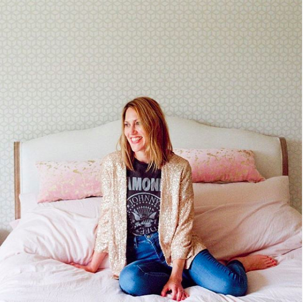 My happy place. A woman sitting on a bed wearing casual clothes and smiling.