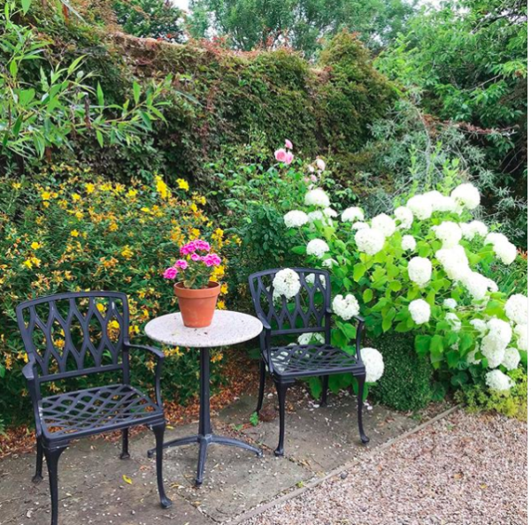 Beautiful garden seating area surrounded by colourful flowering plants.