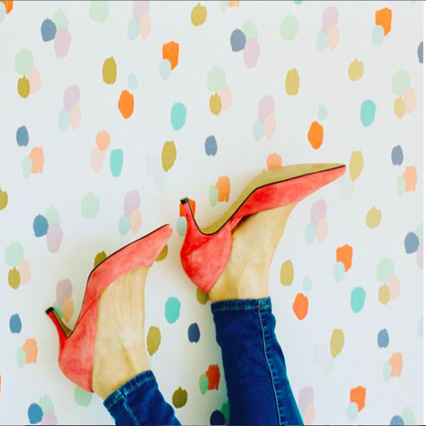 Image of a woman's feet in red high heels on patterned wallpaper