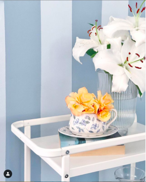 Beautifully styled table next to pastel blue striped wallpaper