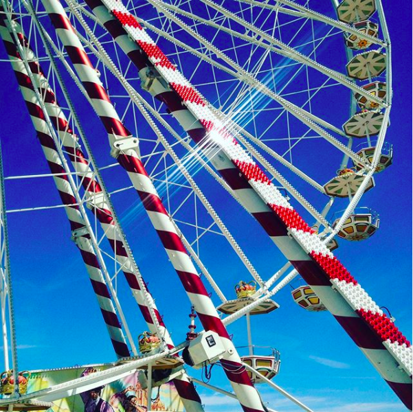 Brightly coloured summer fair ferris wheel in the sunlight