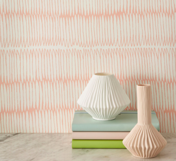 Subtle pink lined wallpaper styled with some pastel coloured books and 2 textured vases.