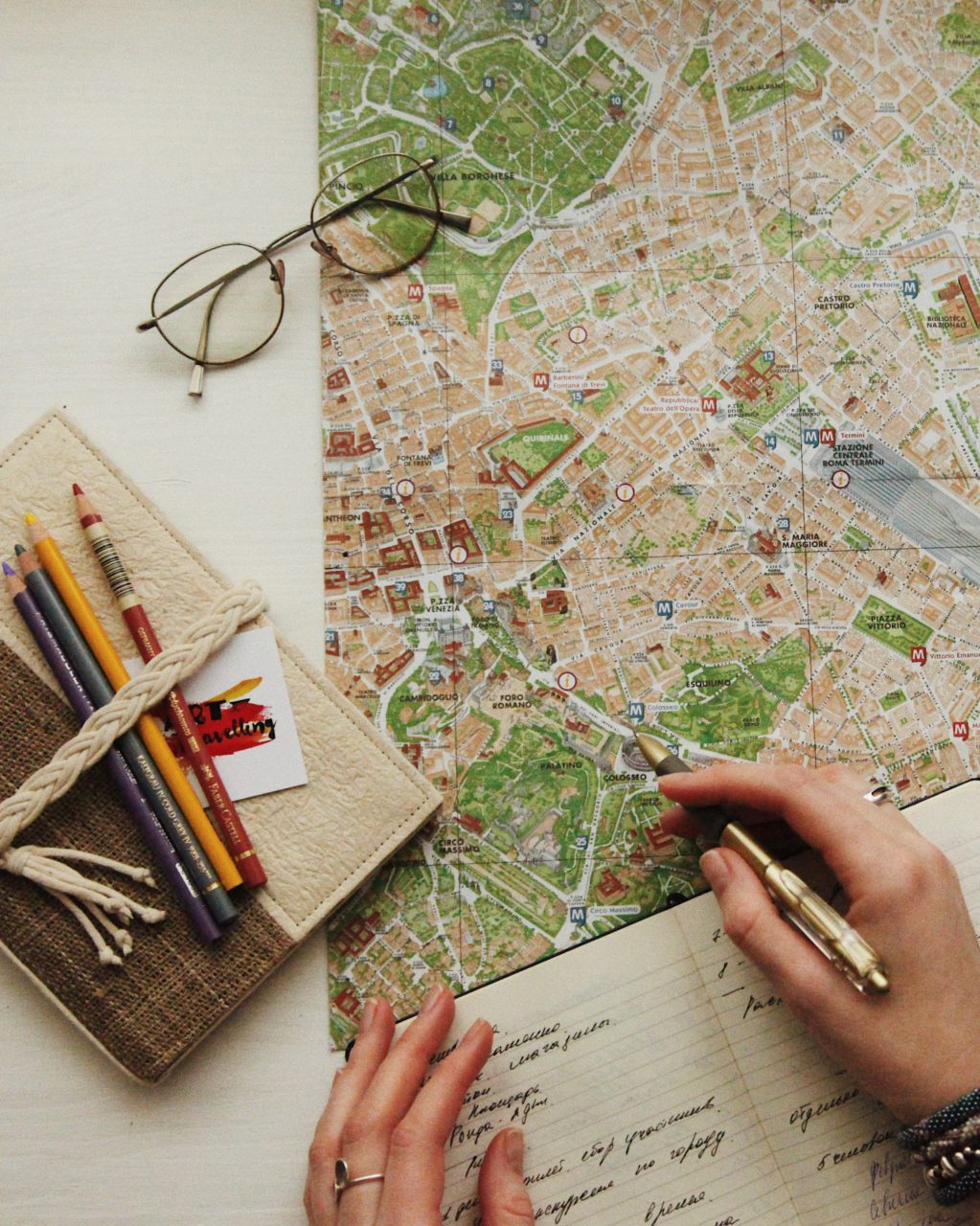 Flat lay image of a map, some glasses and pens