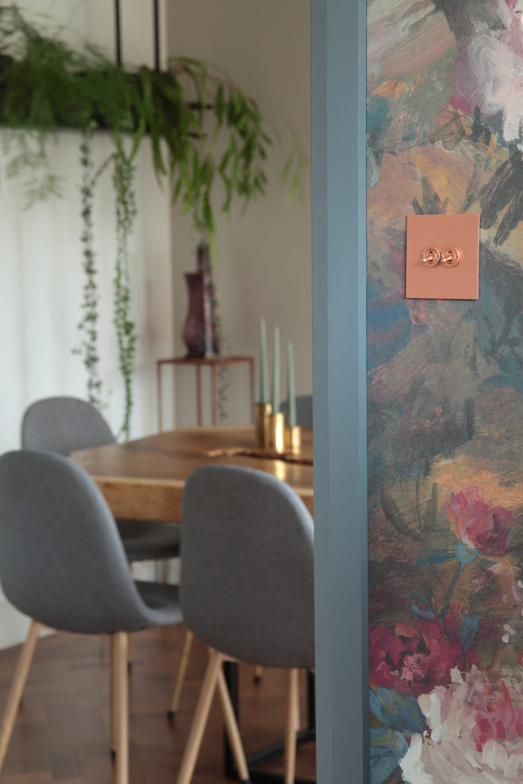 Lightswitch on wall with floral wallpaper with dining room behind 