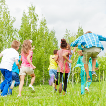 Kids running and playing in a field on a sunny day.